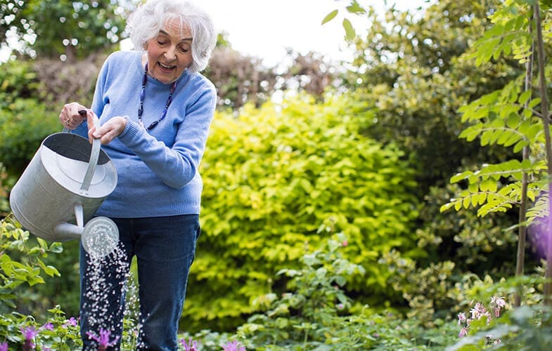 Senior-Woman-Watering-Flowers-In-Garden-692897894_3869x2579.jpg