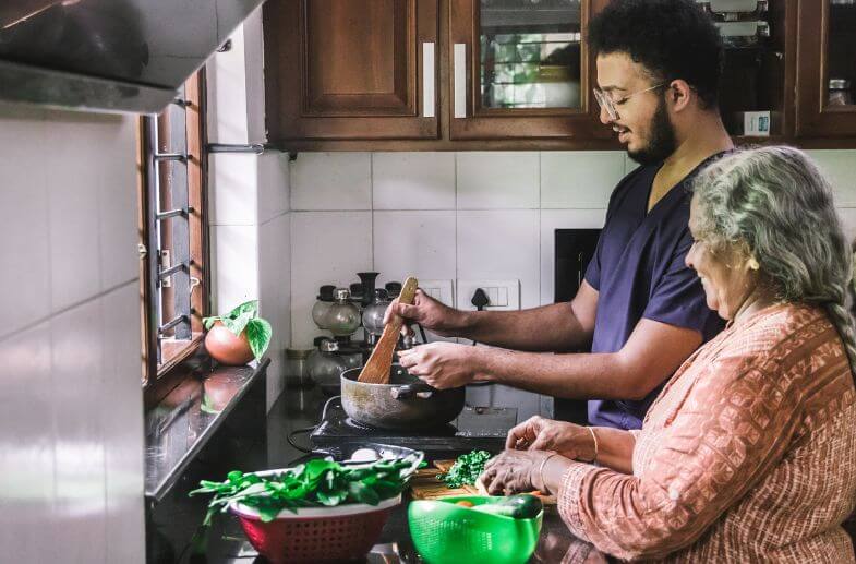 Grandson helping his grandmother prepare a meal in the kitchen