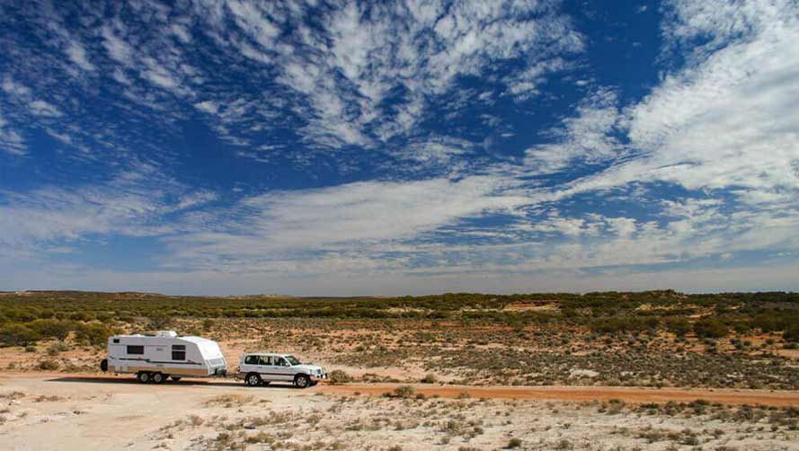 Large 4WD towing caravan across Australian outback