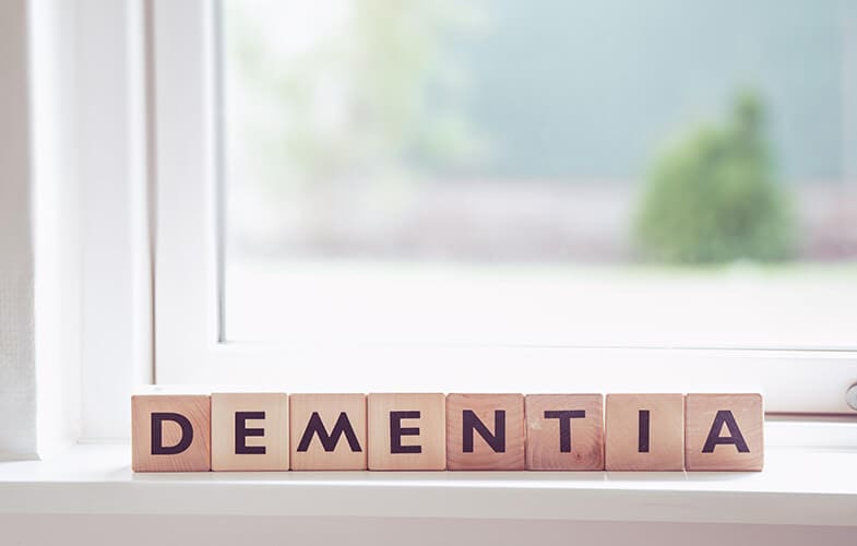 Wooden blocks spelling out dementia, sitting on a sunlit windowsill