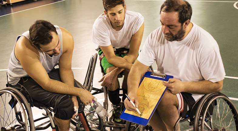 Three men in wheelchairs look at a clipboard