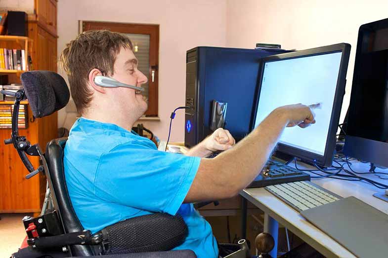 Disabled man in a wheelchair using his computer