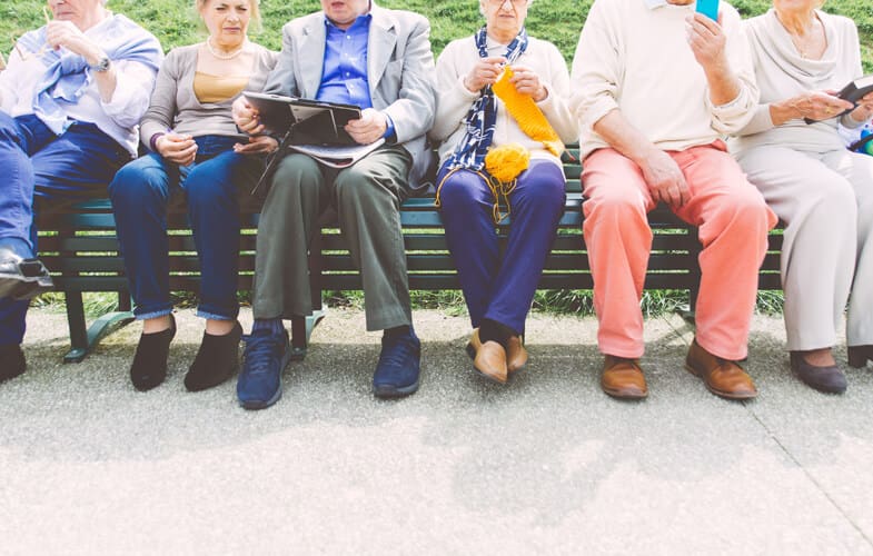 A group of 6 seniors sitting on a park bench
