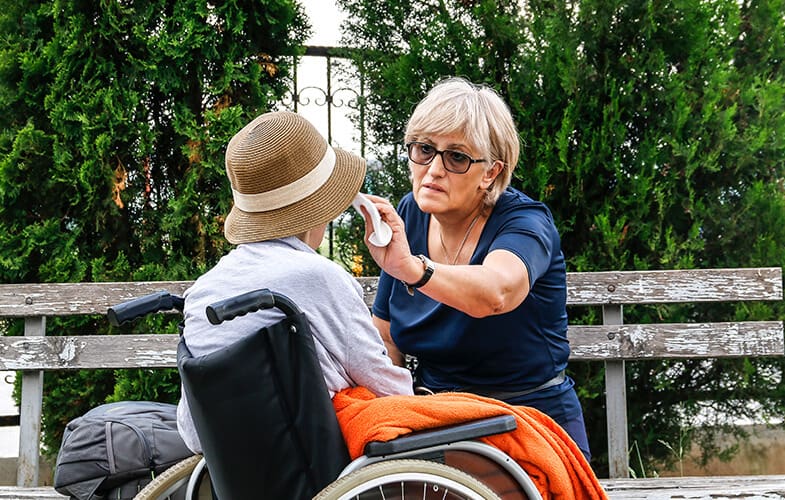 Middle-aged woman wiping the face of an elderly person in a wheelchair