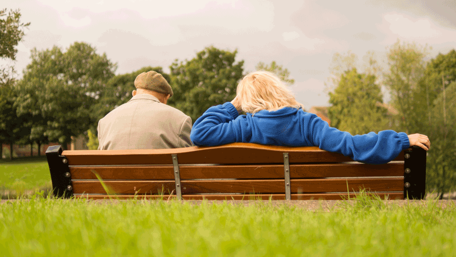 Two elderly people sitting on a park bench
