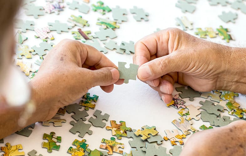 Two hands holding the same jigsaw puzzle piece