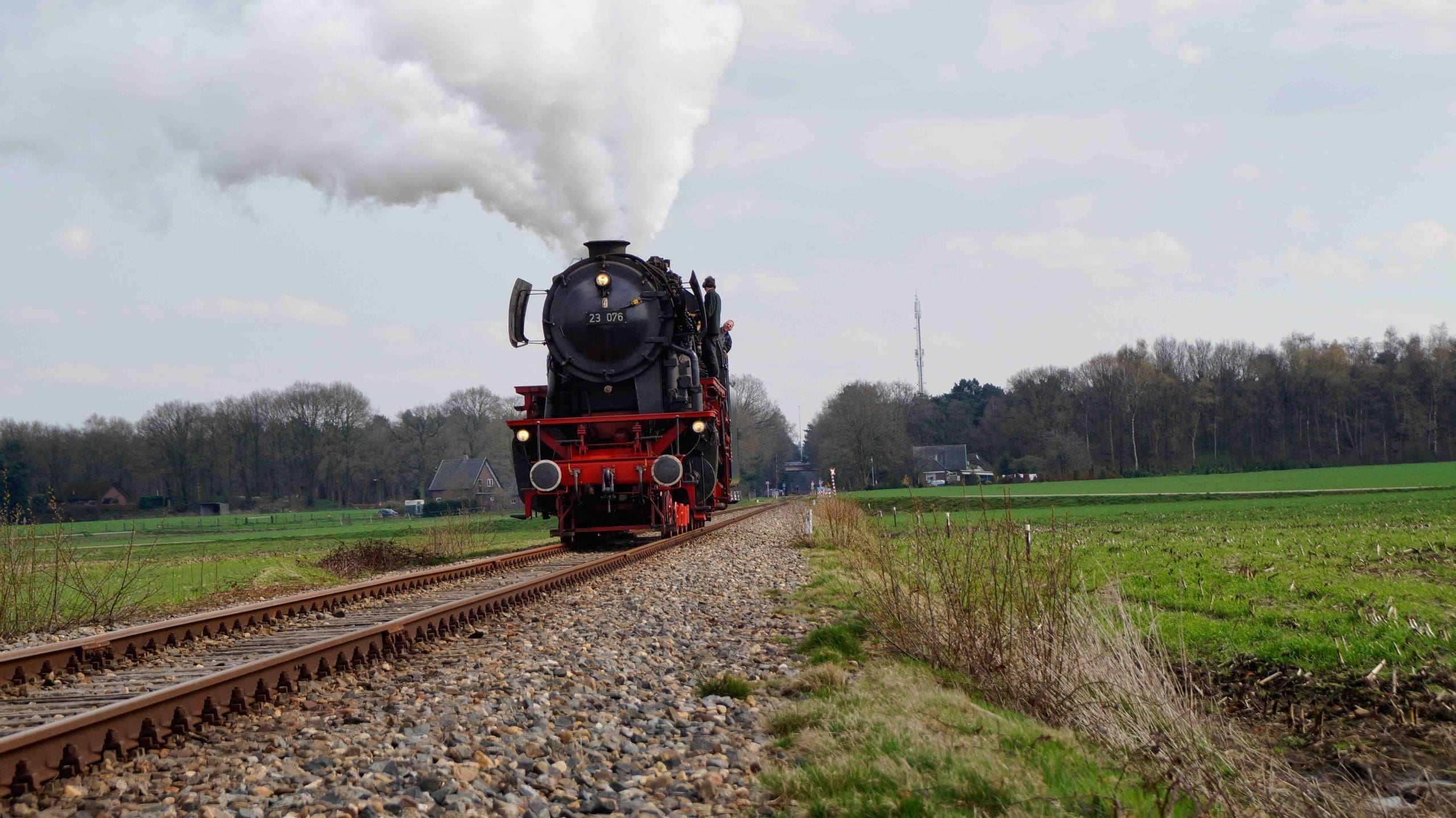 A black and red steam train on a country railway