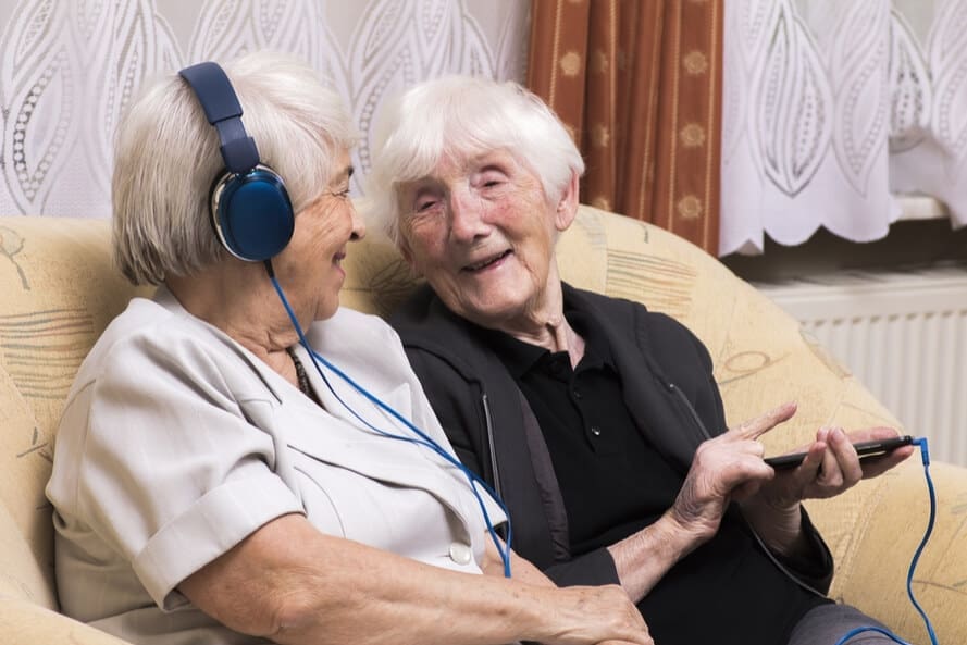Two senior women listening to music with headphones