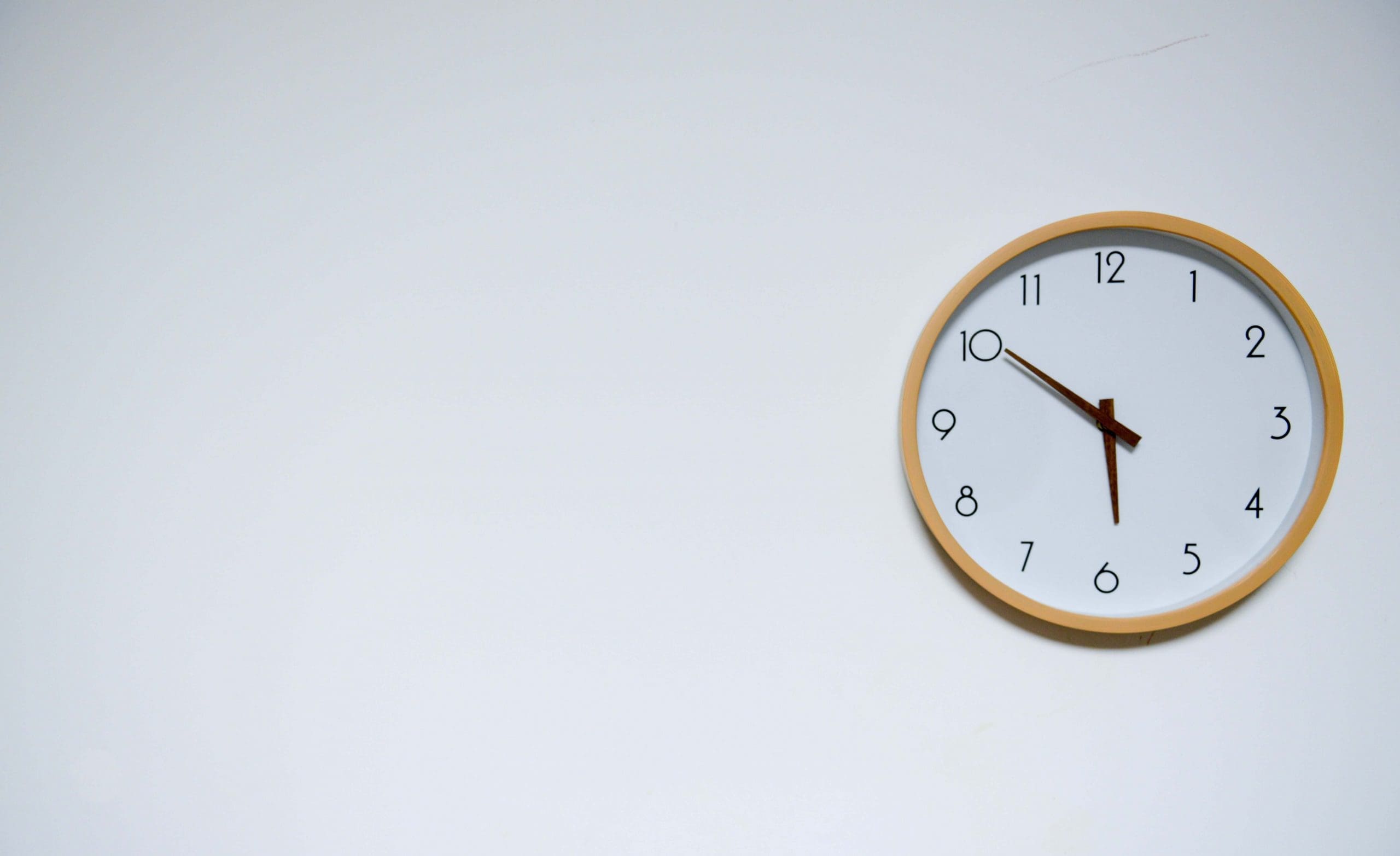 White and gold round wall clock on white wall
