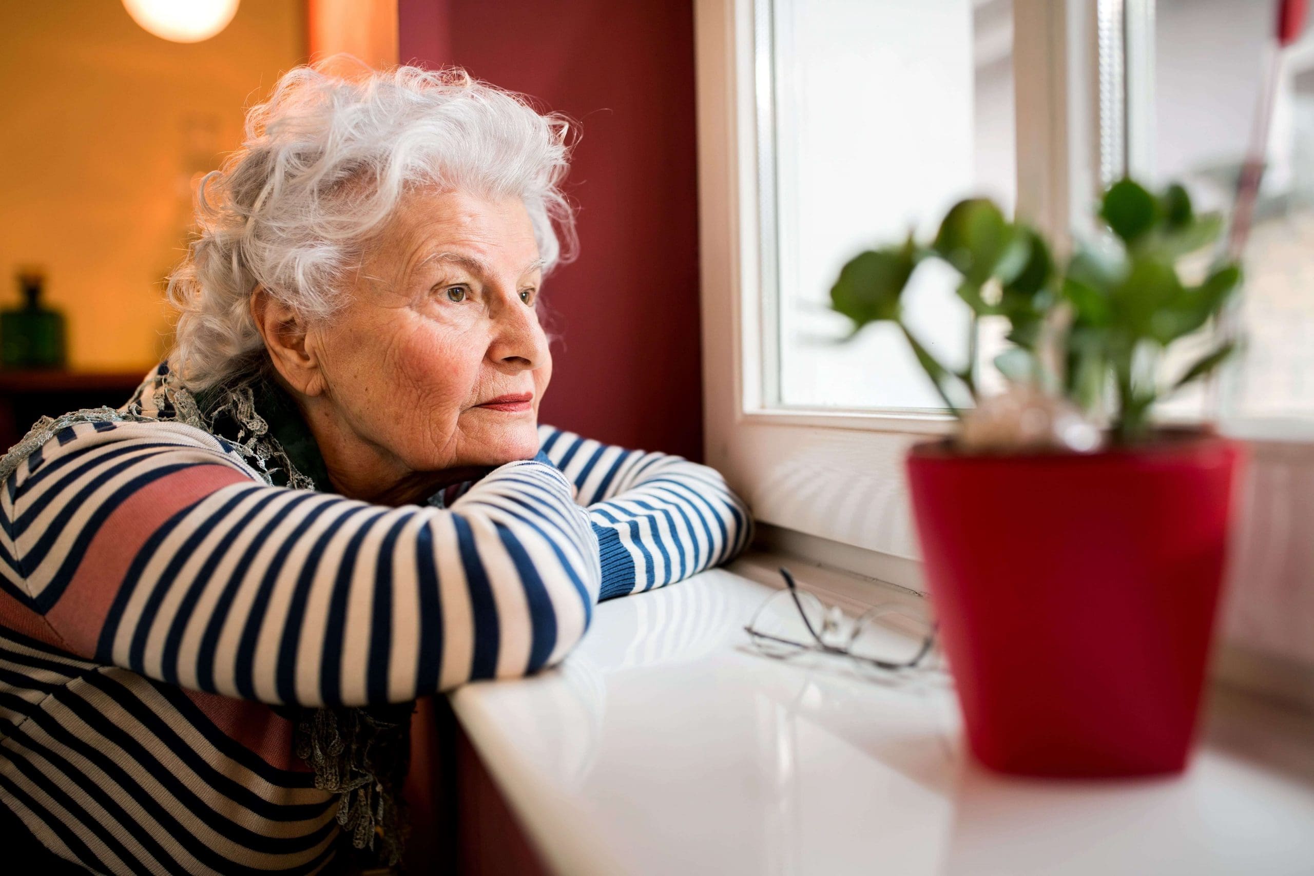 Elderly woman staring longingly out a window