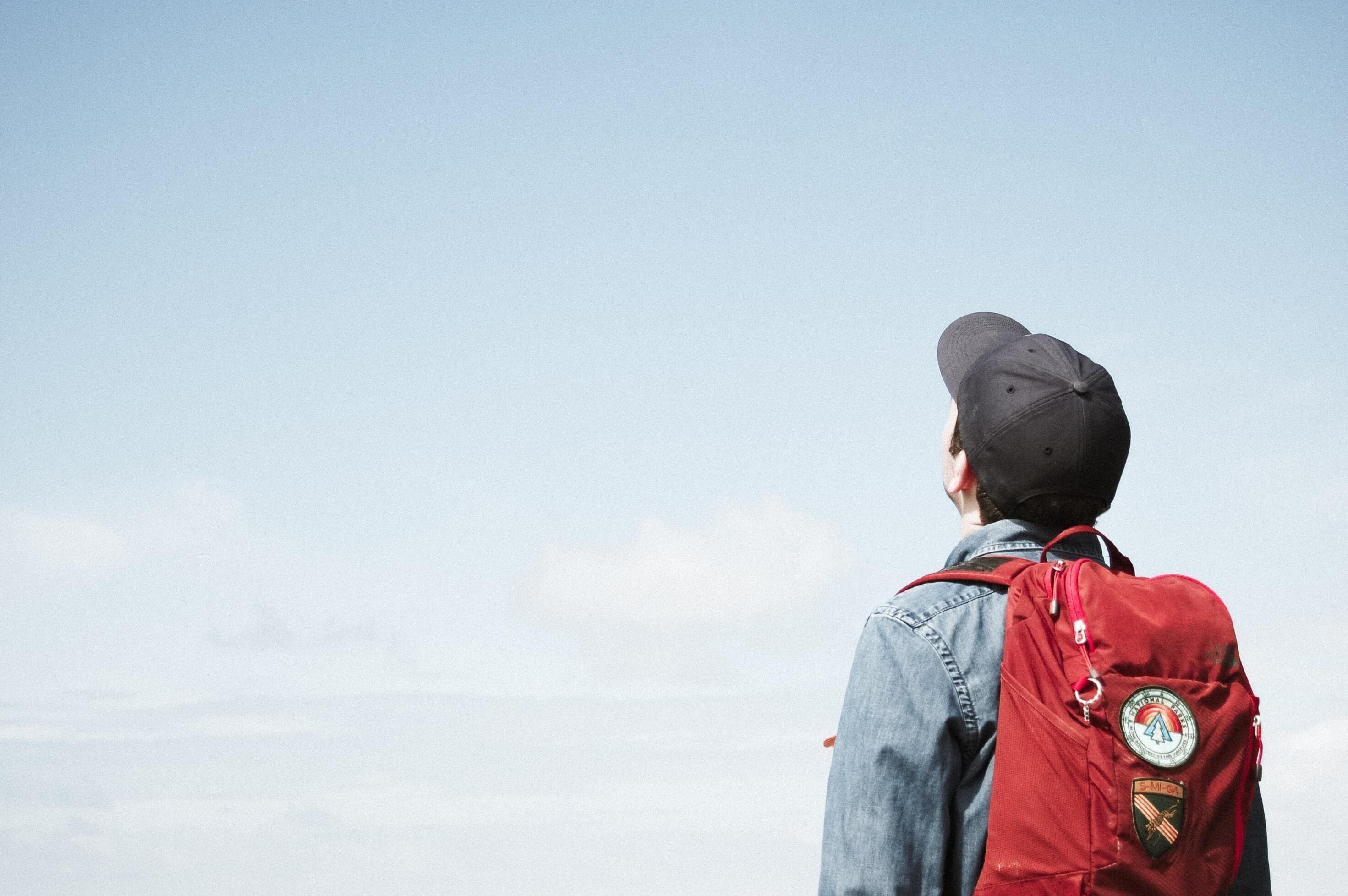 Teenage boy wearing a backpack and staring at the sky
