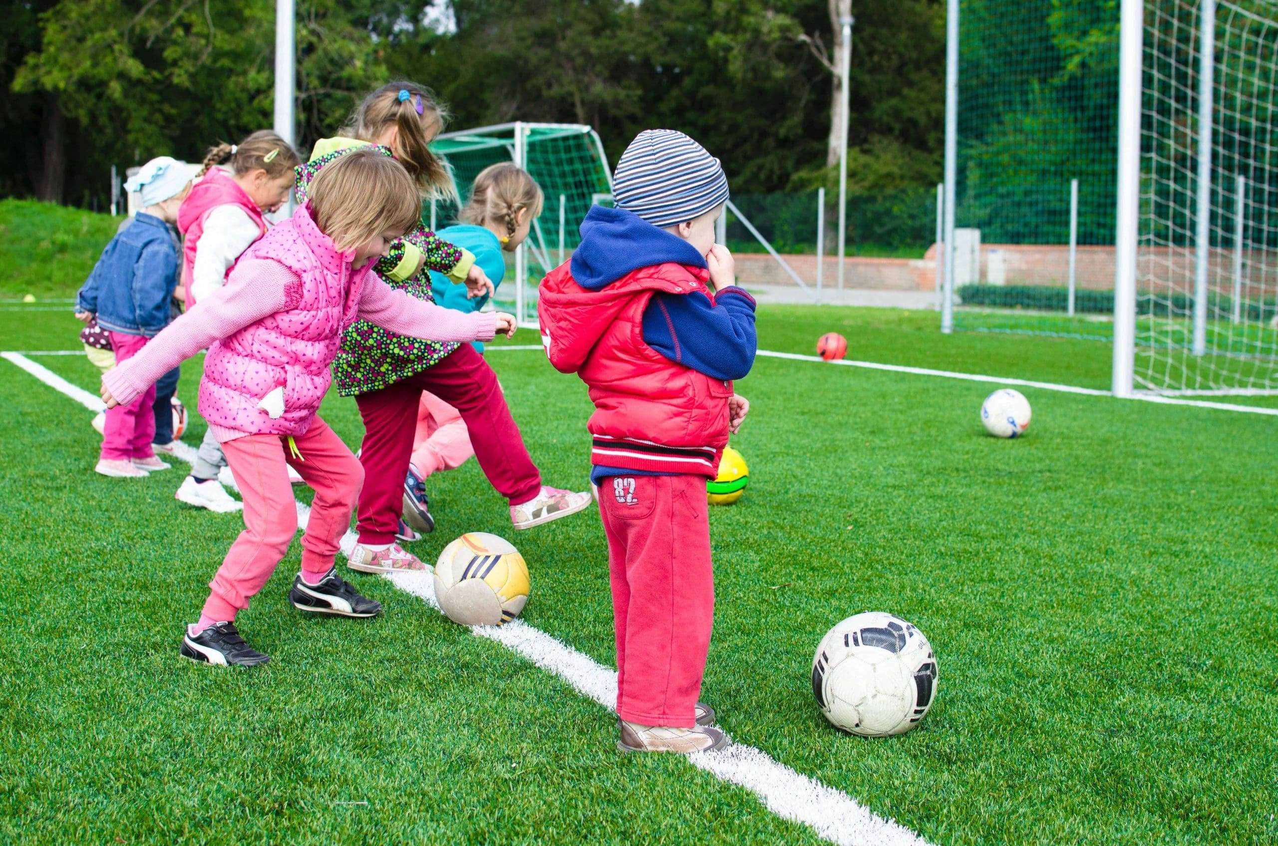 Young children lining up to kick soccer goals