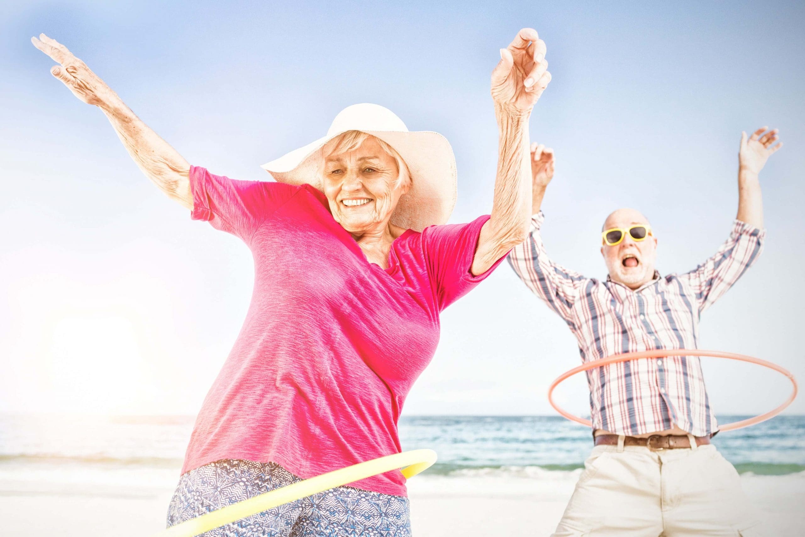 Happy older couple with hula hoops on the beach