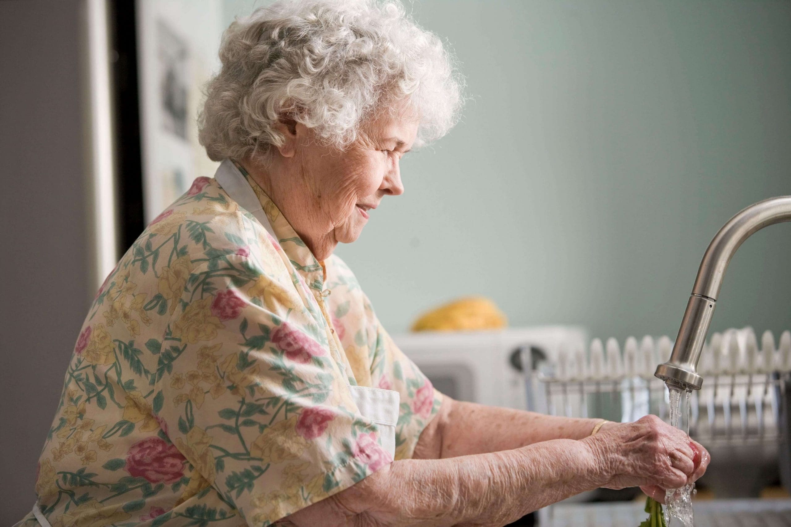 Senior woman washing her hands at the kitchen sink