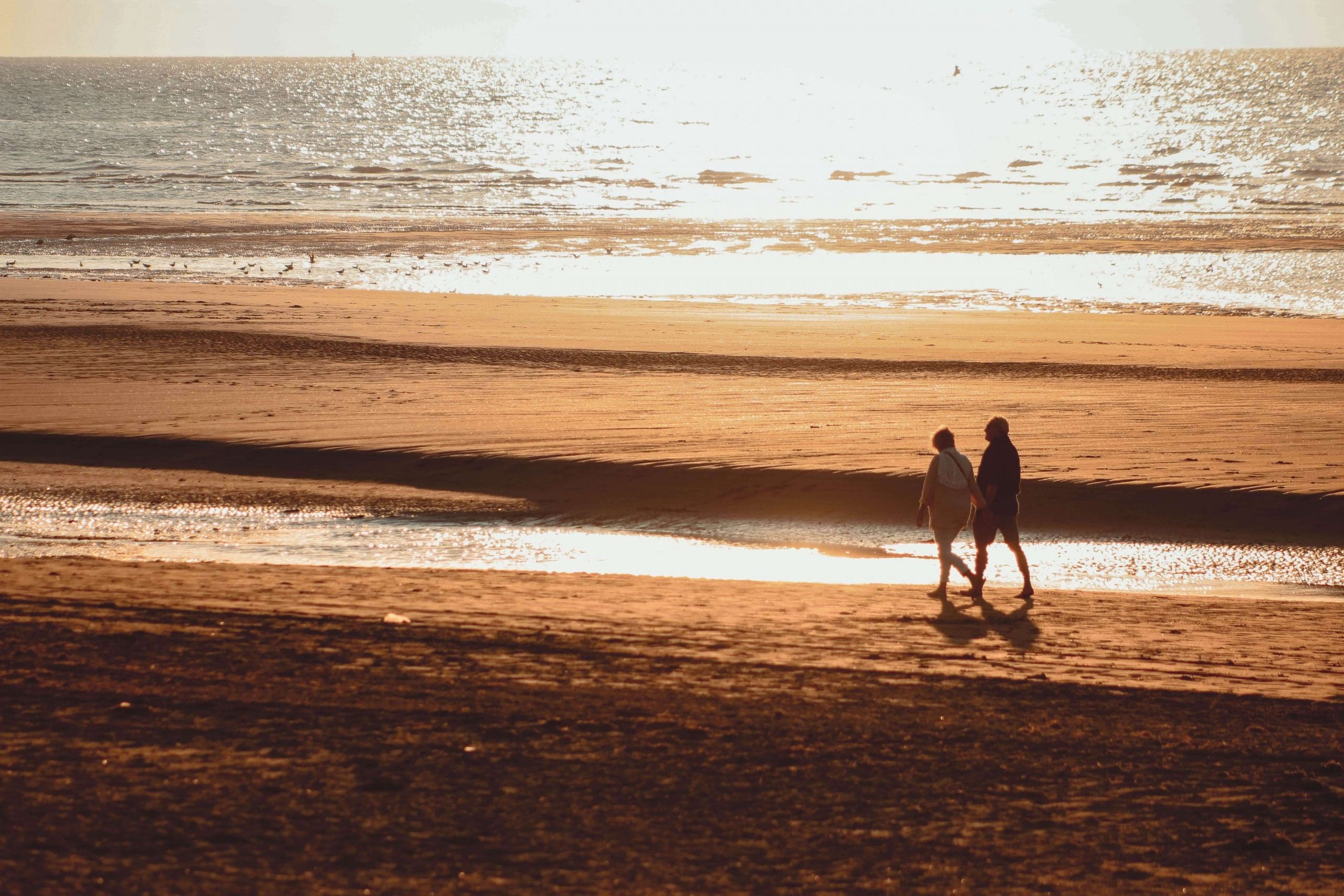 Older couple walking on the beach at sunset