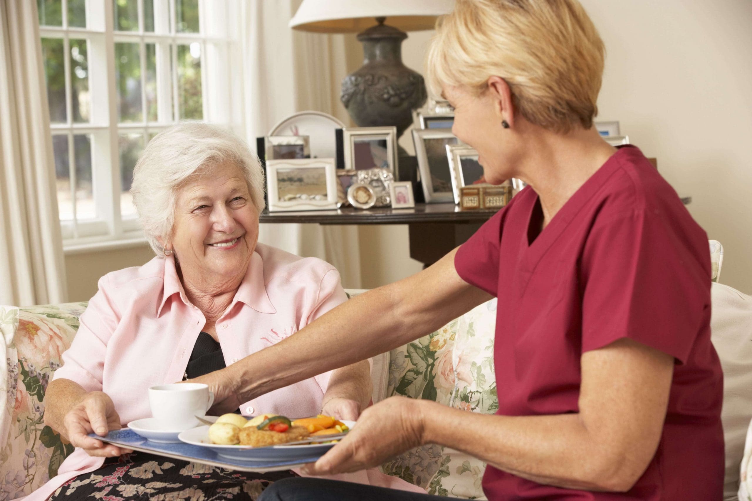 Home care worker helping senior woman with meal preparation