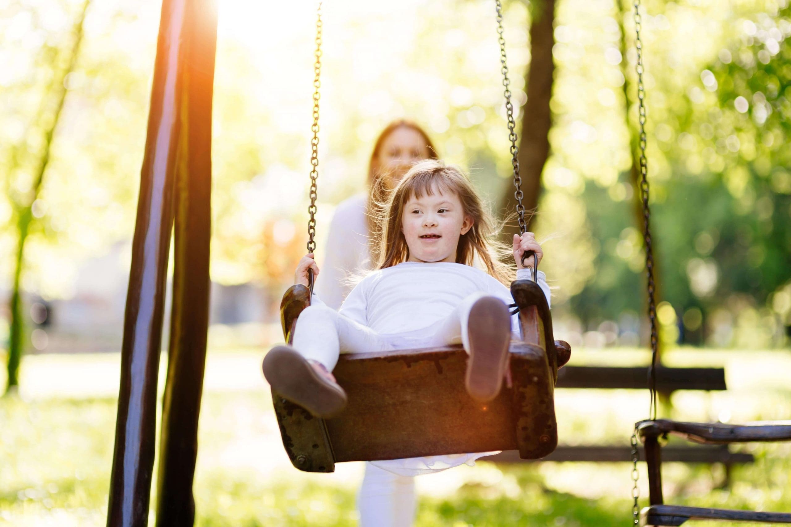 A young girl with Downs Syndrome playing on a swing