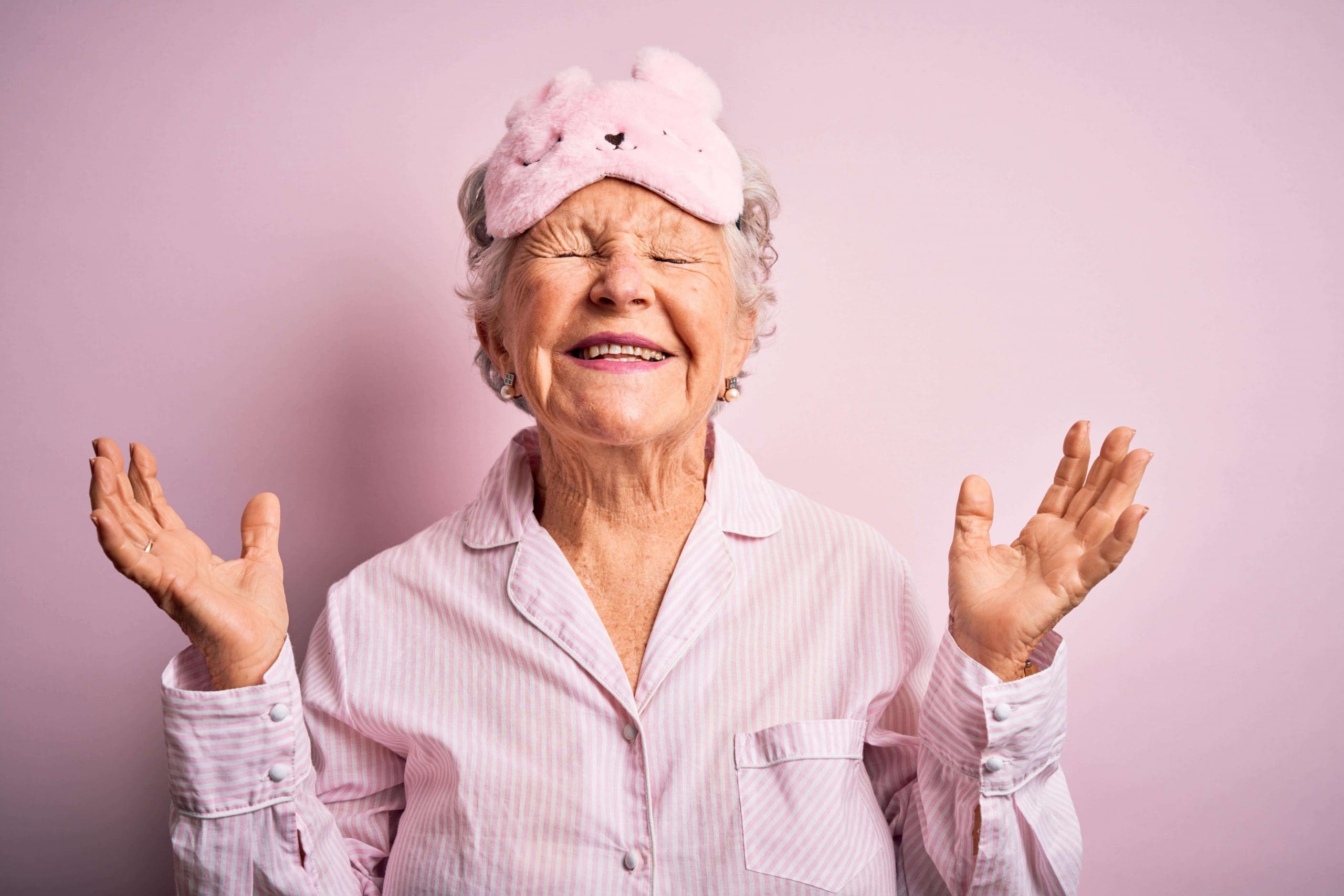 Senior woman in pink pajamas and a pink bunny face mask
