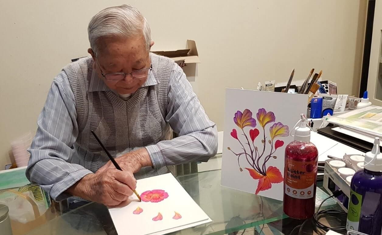 Vietnamese man painting watercolour flowers in his home