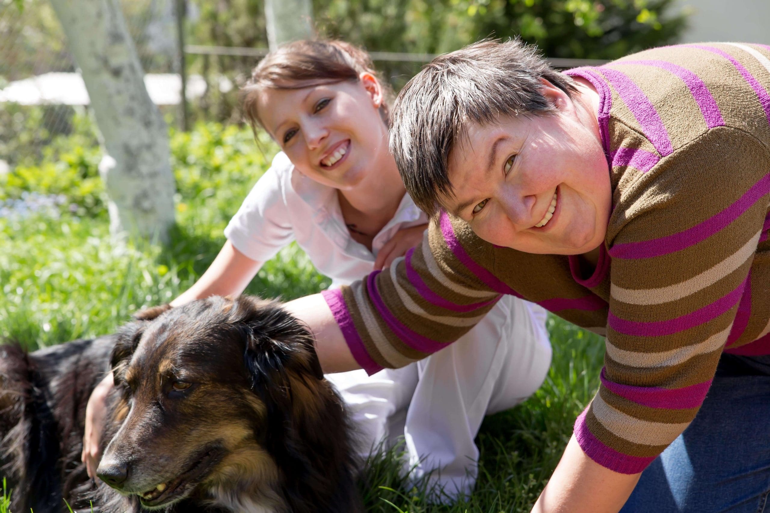 Woman with disability and her carer playing with a dog