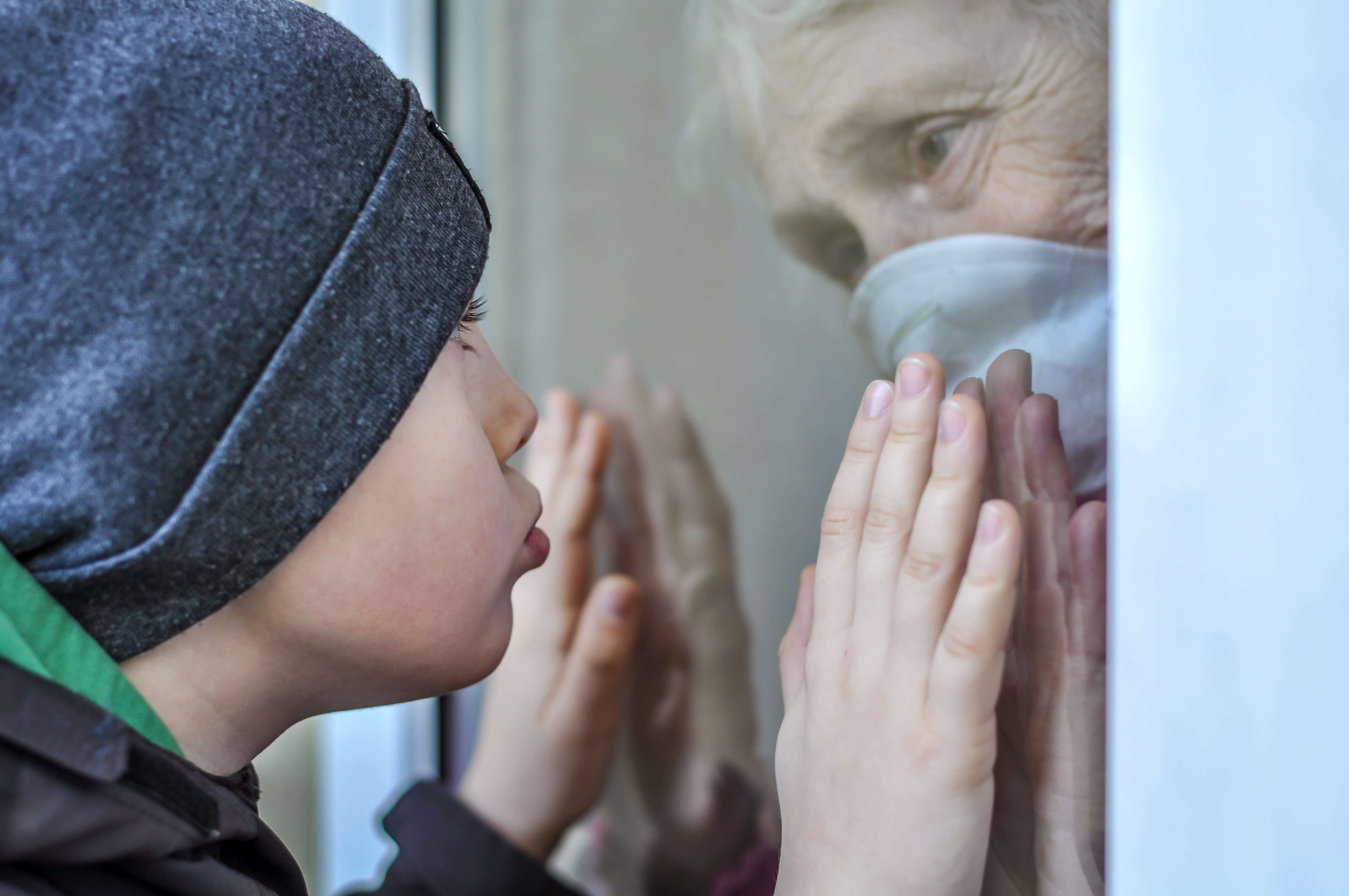elderly woman and grandson separated by glass window