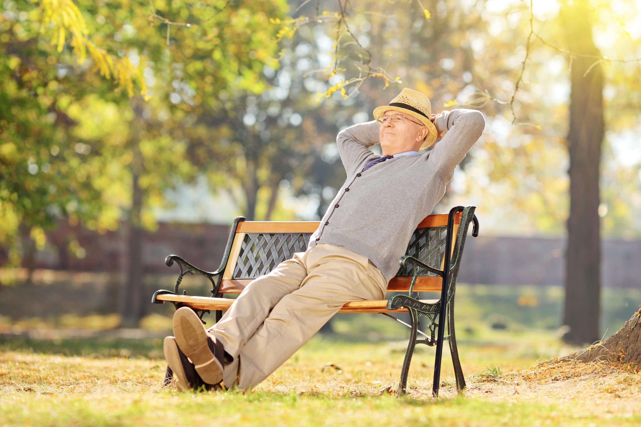 Senior man stretched out on a park bench with hands behind his head