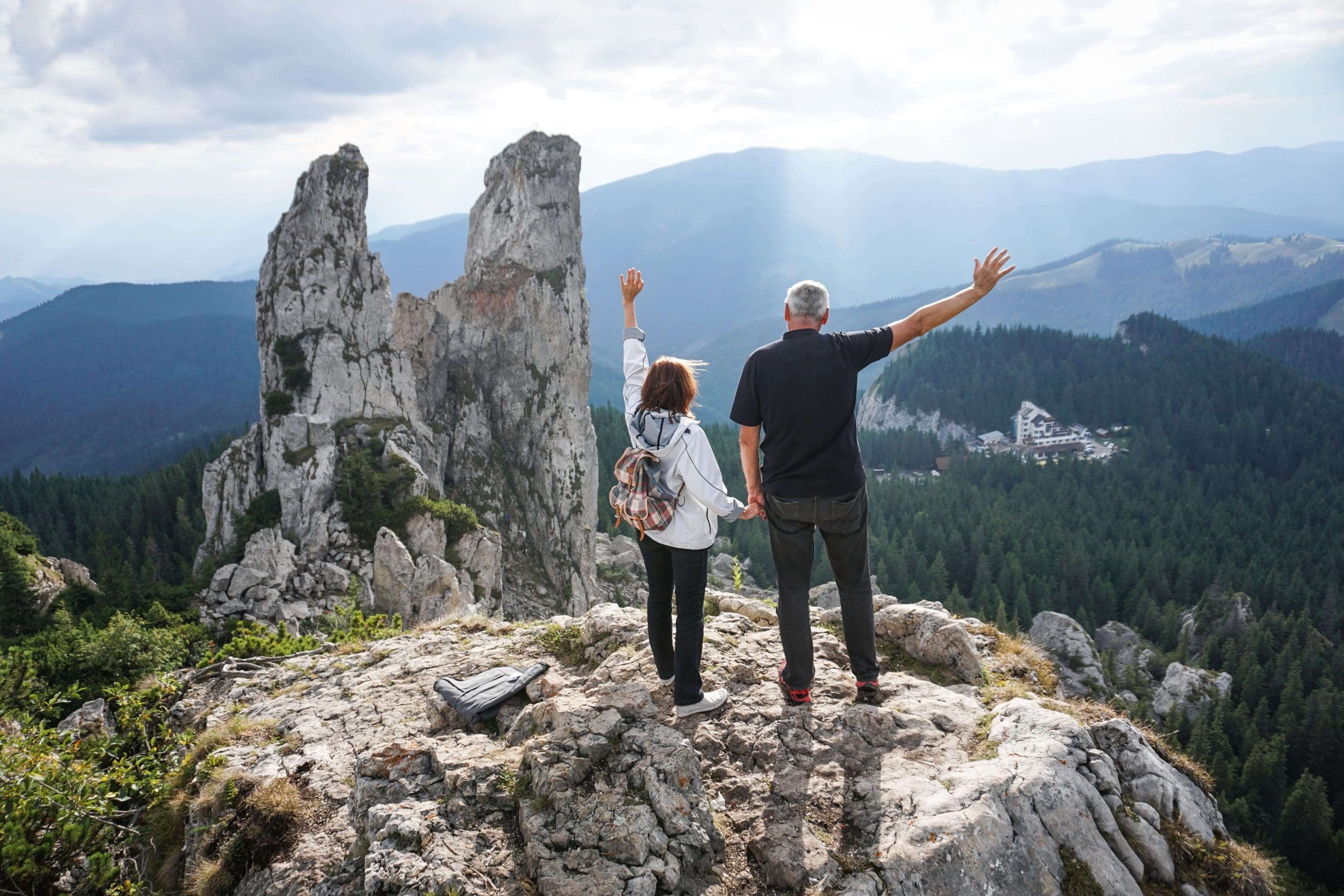 Senior couple at the top of a mountain reaching into the sunset