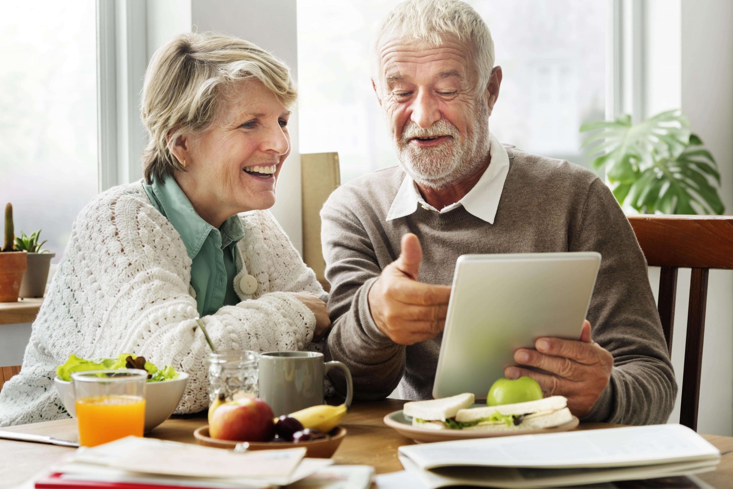 Senior couple looking at an iPad together over lunch