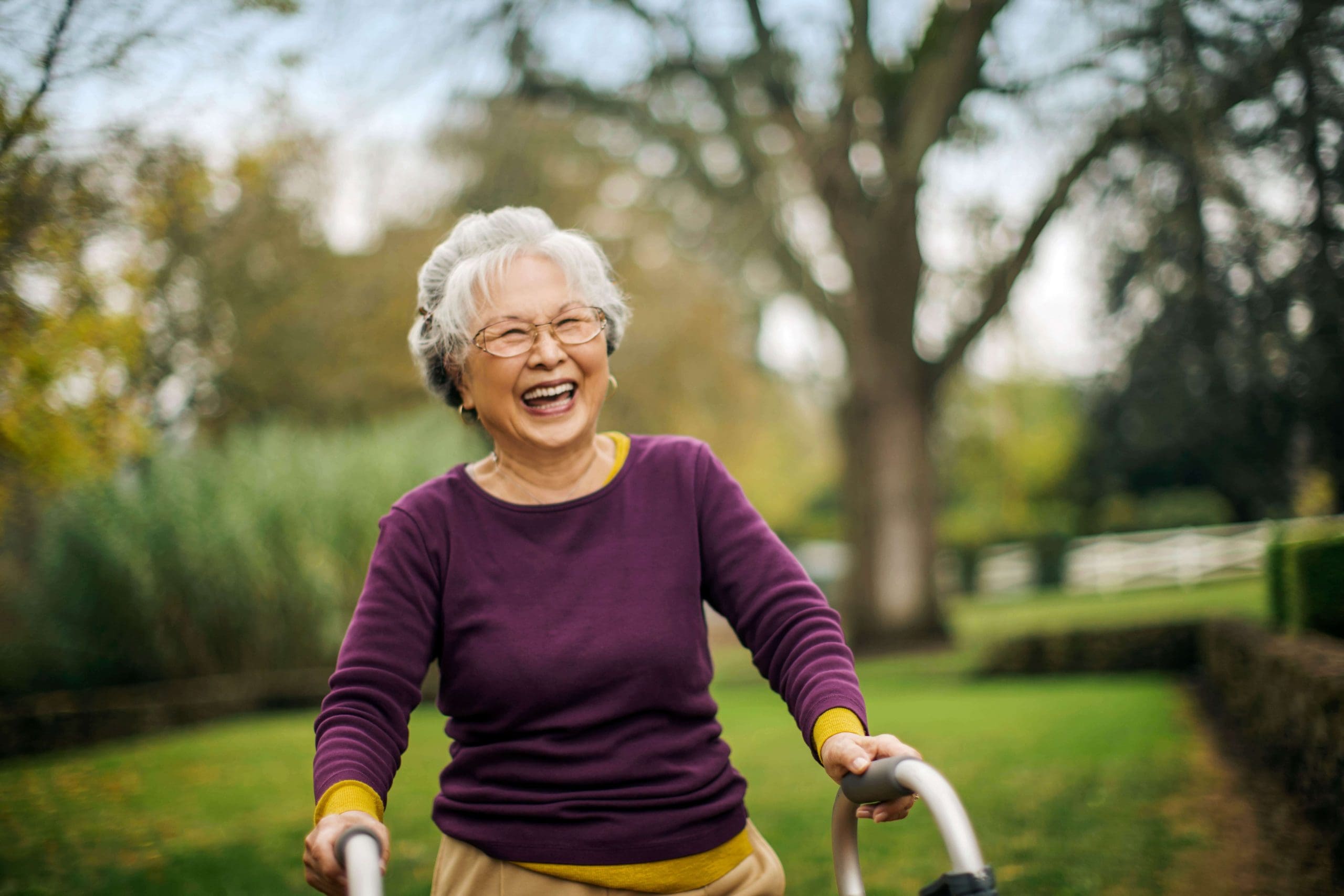 Older Asian woman happily using a walking aid to help her exercise