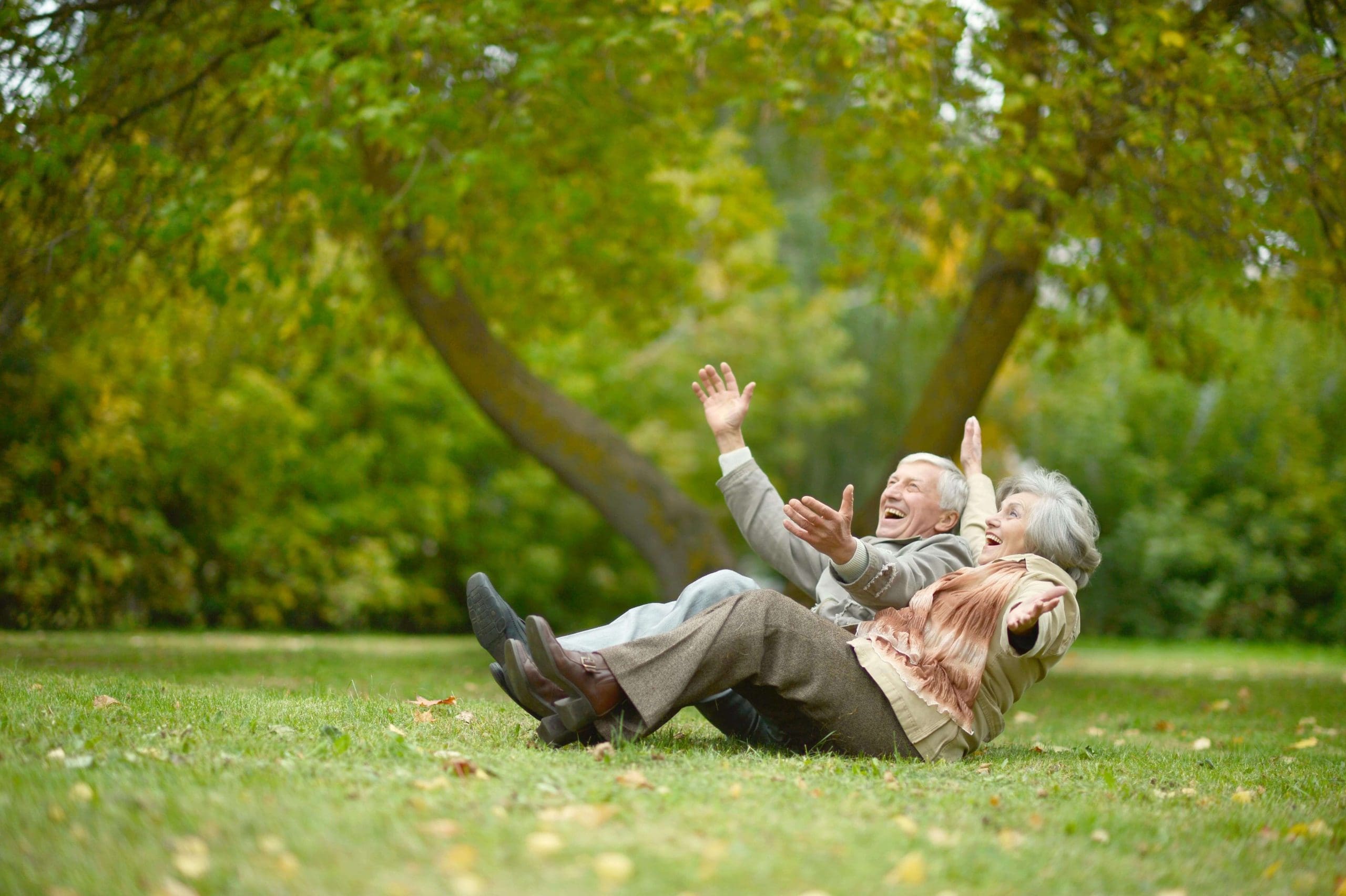 Senior couple in a park lying back and laughing