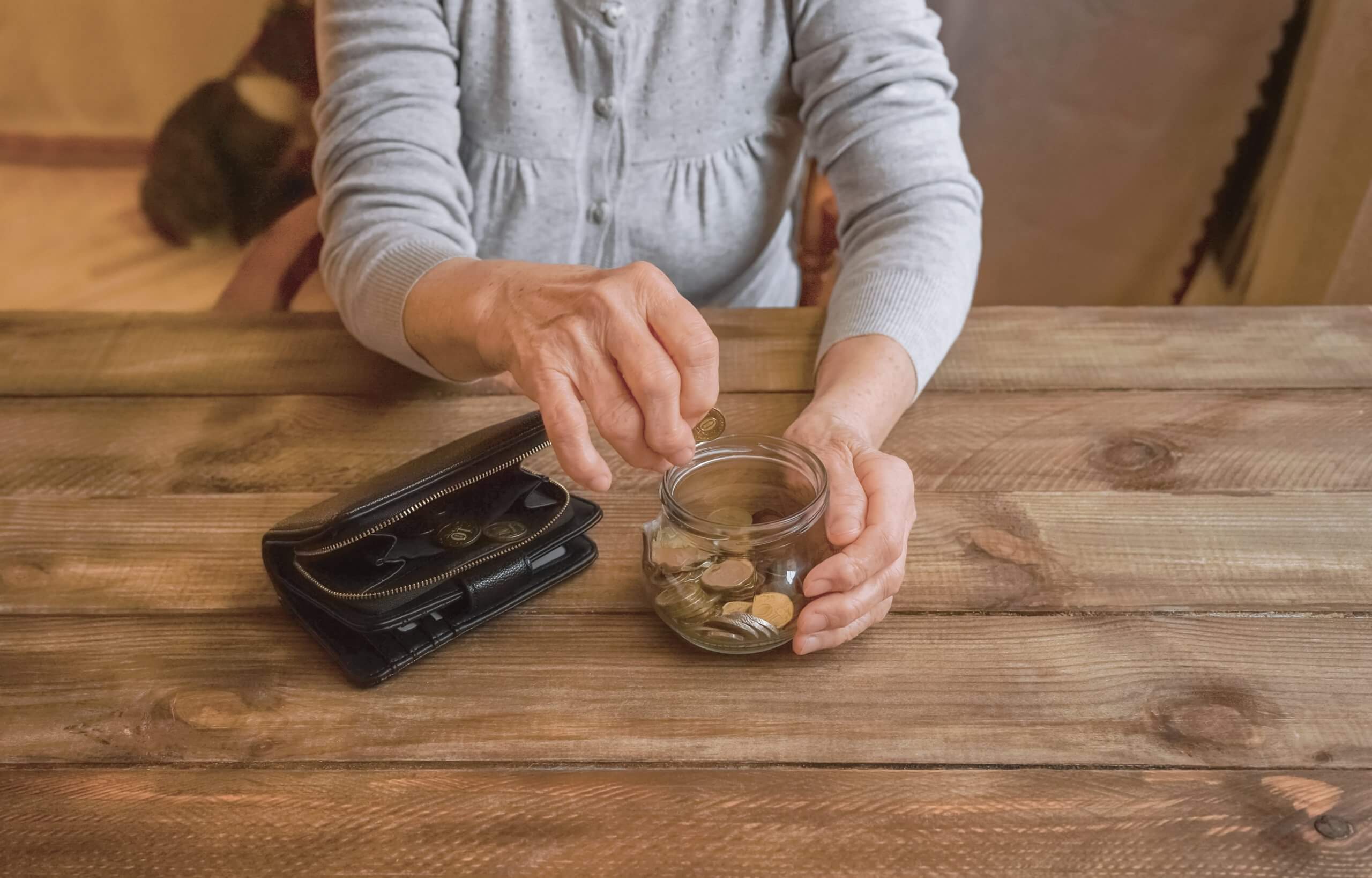Elderly hands placing coins in a jar