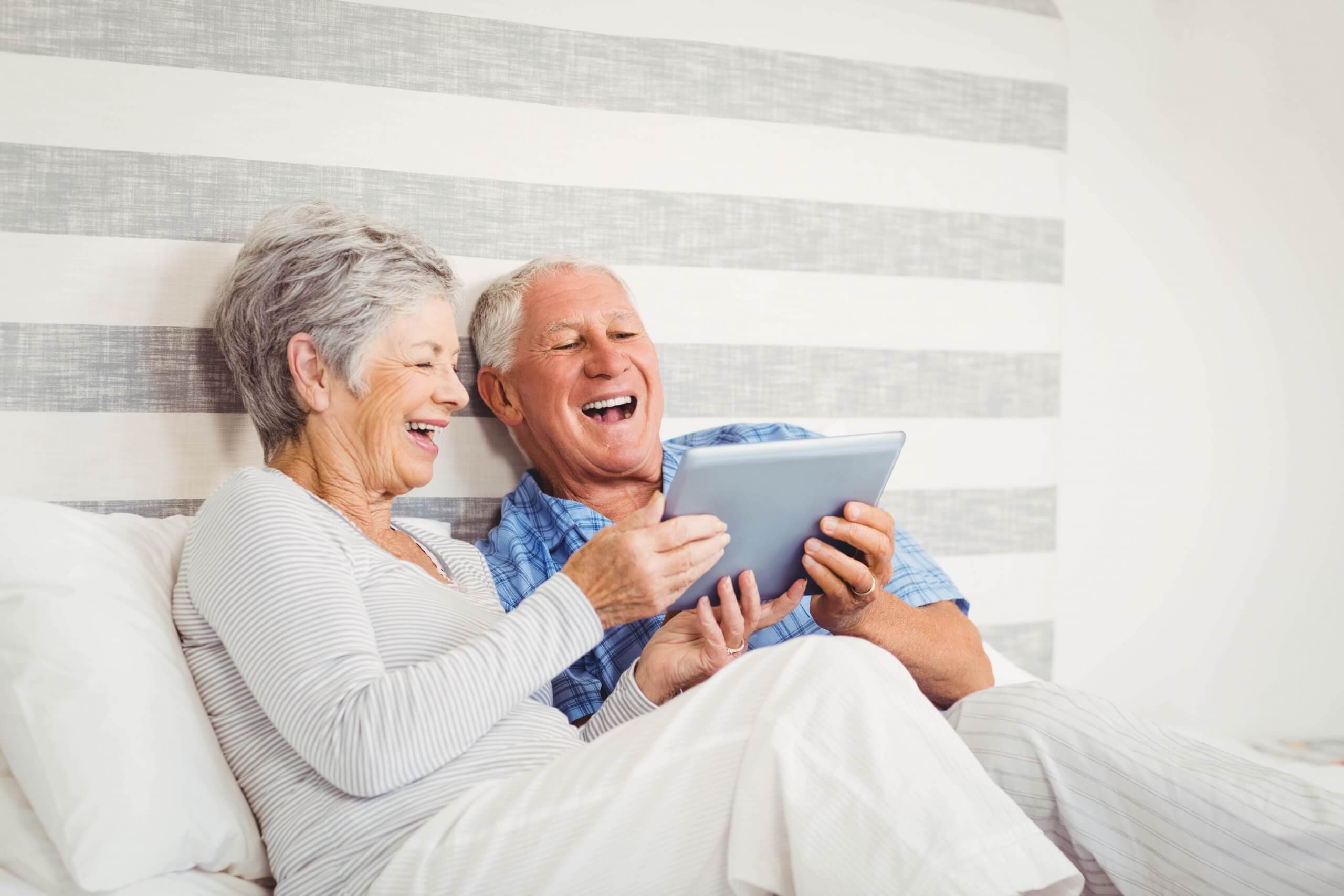 Senior couple happily playing with an iPad