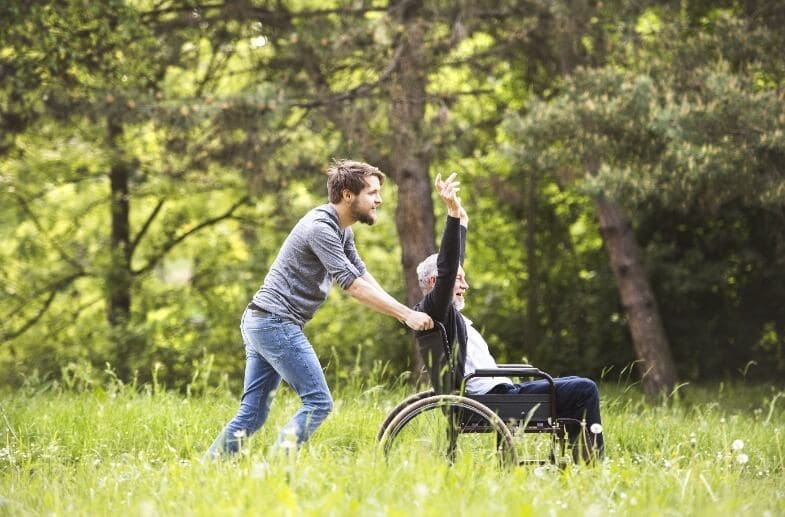 Young male caregiver with senior man in a wheelchair