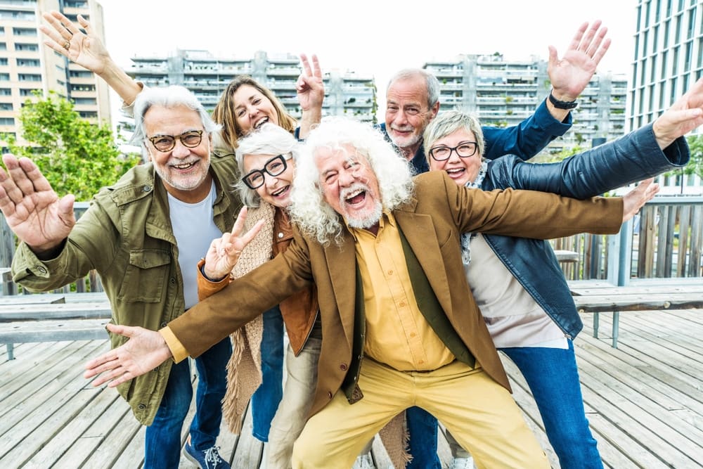 Happy group of senior people smiling at camera together outside